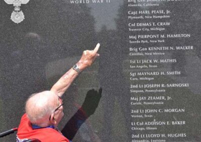 Veteran pointint to names on a wall at the Air Force Memorial