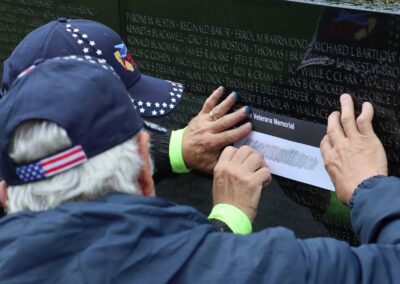 "A veteran carefully makes an etching on the Vietnam Veterans Memorial Wall, capturing the name of a fallen soldier to honor their memory and sacrifice."