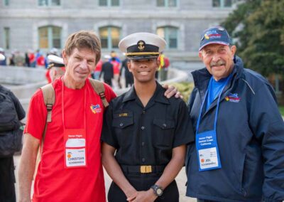 Annapolis cadet standing with a veteran and their guardian, sharing a moment of respect and camaraderie.