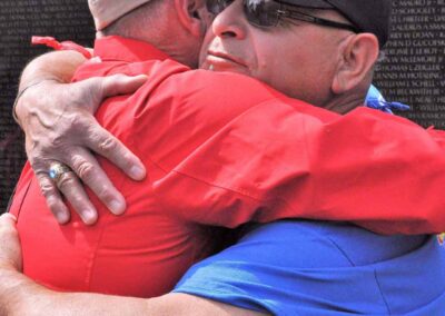 Veteran and guardian sharing an emotional hug at the Vietnam Veterans Memorial Wall.