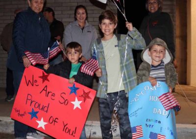 Kids holding "Welcome Home" signs at the airport as veterans return from their Honor Flight trip.