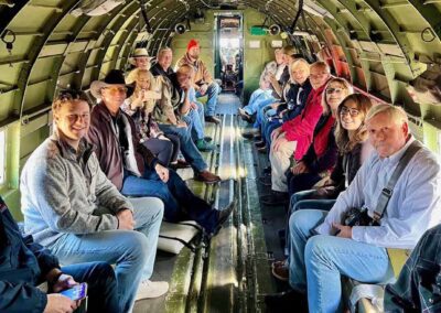 "A group of people riding aboard a vintage C-47 plane as part of a fundraiser event, soaring through the sky to support a charitable cause."